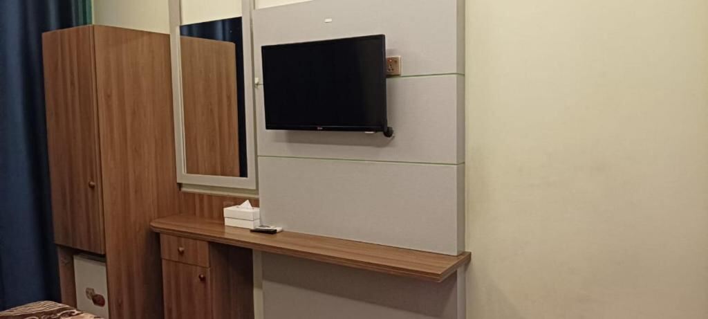 Flat-screen TV, desk and wardrobe inside a Homa Hotel room